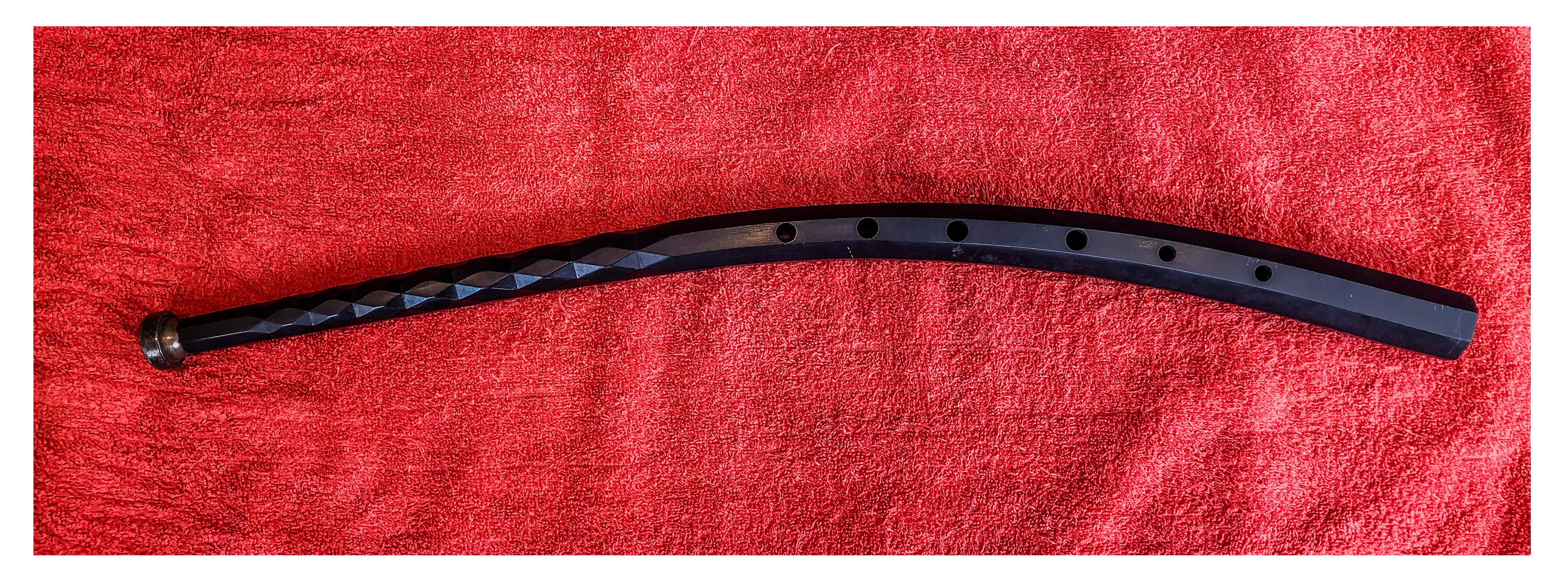 Musical instrument with a trumpet-like mouthpiece and a short, black, curved body with finger-holes